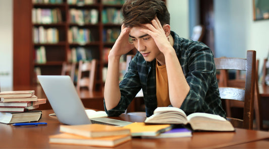 Student mit Stress beim Lernen am Laptop in der Bibliothek