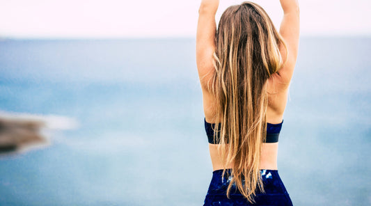 Frau mit langen Haaren streckt sich am Meer