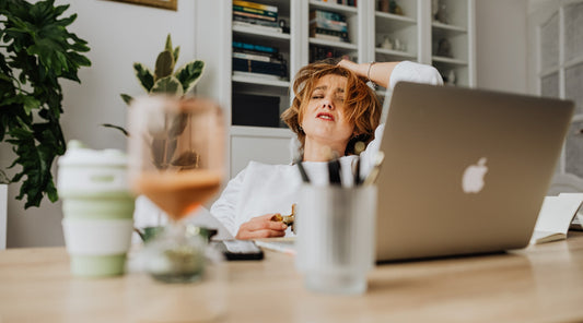 Gestresste Frau sitzt am Schreibtisch vor Laptop im Homeoffice