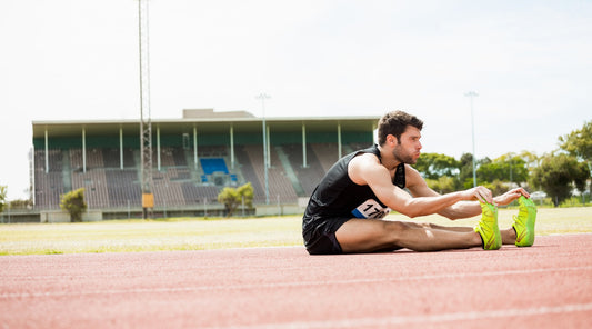 Triathlet beim Dehnen auf der Laufbahn – Vorbereitung auf Wettkampf durch Stretching