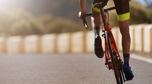 Triathlet beim Rennradfahren auf offener Straße Fokus auf Beinmuskulatur
