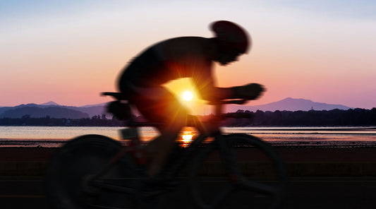 Rennradfahrer fährt bei Sonnenuntergang am See