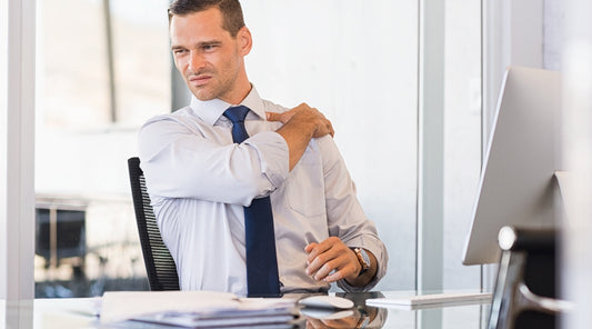 Mann mit Schulterverspannungen am Arbeitsplatz