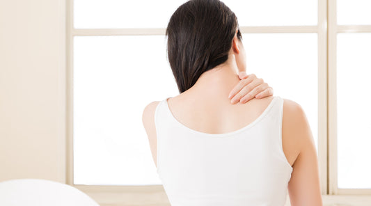 Frau fasst sich wegen Verspannung an die Schulter