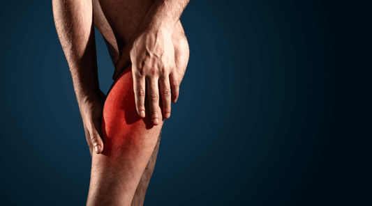 Eine Person hält sich mit beiden Händen das Knie, das rot markiert ist, um Schmerzen oder eine Verletzung zu symbolisieren, vor einem dunkelblauen Hintergrund.