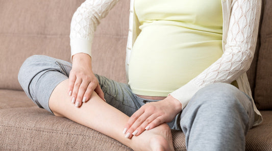 Schwangere Frau mit Wassereinlagerungen in den Beinen auf dem Sofa