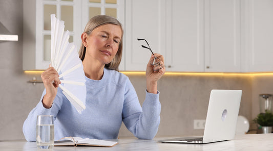 Ältere Frau mit Hitzewallung fächert sich Luft zu