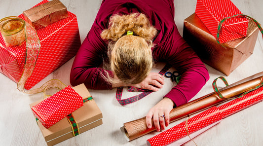 Frau erschöpft beim Geschenke einpacken an Weihnachten
