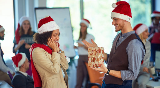 Kollegen tauschen Weihnachtsgeschenke bei Weihnachtsfeier im Büro
