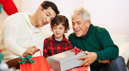 Drei Generationen Männer packen zusammen Weihnachtsgeschenke aus