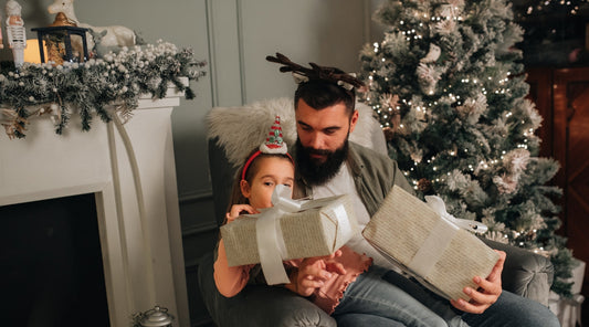 Vater und Tochter mit Weihnachtsgeschenken vor dem Tannenbaum