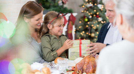 Enkelkind überreicht Geschenk an Großvater bei Weihnachtsessen